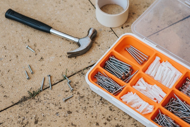 an orange toolbox with screws and nails in it and a hammer next to it